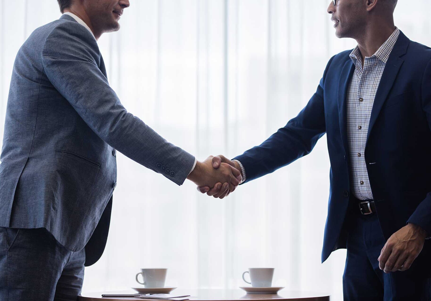Two business men shaking hands with each other after a deal. Businesspeople shaking hands making a necessary agreement during a meeting.